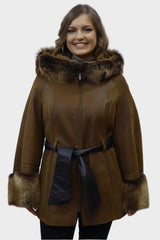 Gewachsene lange Damen Lammfelljacke mit Kapuze aus Toskana Fell und Ärmellänge. Das Modell ist antik braun ,hat ein Reißverschluss und ein Gürtel