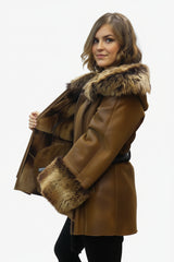 Gewachsene lange Damen Lammfelljacke mit Kapuze aus Toskana Fell und Ärmellänge. Das Modell ist antik braun ,hat ein Reißverschluss und ein Gürtel